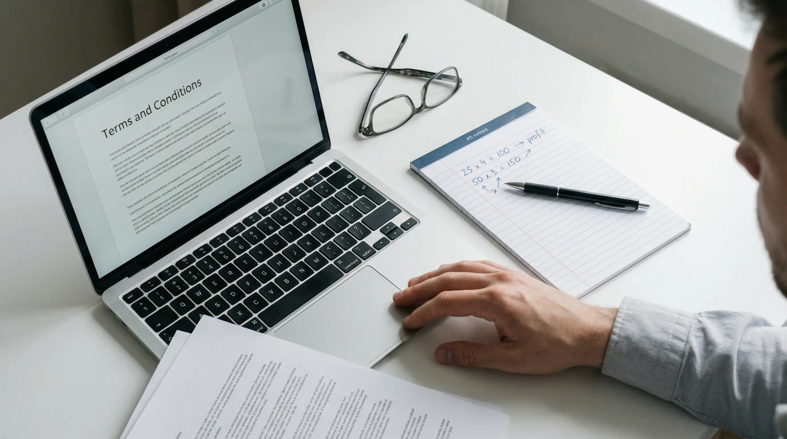 Close-up of a person reviewing casino bonus terms on a laptop with a notepad showing handwritten notes